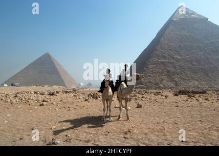 Pyramides, Gizeh, Égypte, 2007. Des cavaliers de chameau en face des Pyramides, les tombes des pharaons Menkaure, Khafre et Khufu, datant d'environ 2000 av. J.-C., Gizeh, Égypte. Banque D'Images