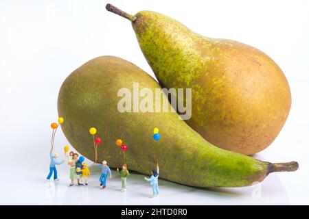 Une mère avec des enfants gaies est debout avec des ballons colorés devant des poires Banque D'Images