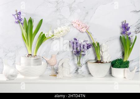 Jacinthe blanche dans un grand bol en porcelaine, figurines de lièvres et un oiseau, sont sur la cheminée contre le mur en marbre blanc. Mise en page. Concept de ressort Banque D'Images