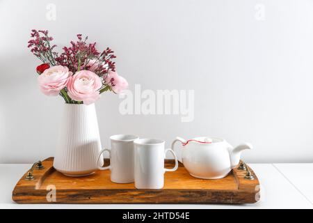 Coupe de beurre rose perse avec plateau en bois brun sur une table blanche. Il est temps de boire du thé. Théière en céramique et deux tasses en porcelaine. Copier l'espace Banque D'Images