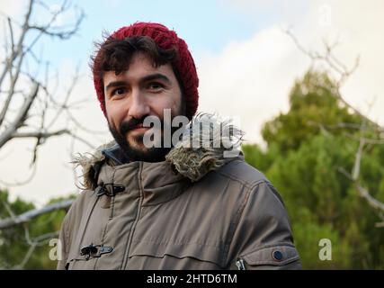 Gros plan portrait du jeune homme avec barbe en regardant l'appareil photo et en souriant. Banque D'Images