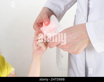 Les mains du médecin bandent le doigt douloureux avec un bandage de l'enfant.Blessure et blessure au doigt chez les enfants Banque D'Images