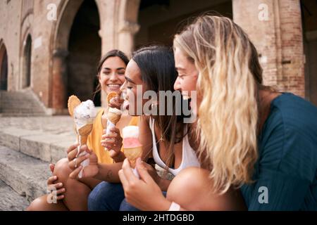 Trois jeunes femmes mangeant des cônes de glace à la ville romaine européenne touristique lors d'une chaude journée d'été pendant leurs vacances Banque D'Images