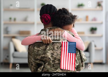 Fille émotive avec drapeau des États-Unis embrassant sa mère Banque D'Images