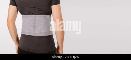 Renfort lombaire sur le corps humain isolé sur un fond blanc. Traumatisme du dos. Corset arrière, support lombaire orthopédique, ceinture de soutien pour les muscles du dos. Plus bas Banque D'Images