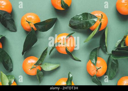 Mandarines fraîches avec feuilles sur fond vert Banque D'Images