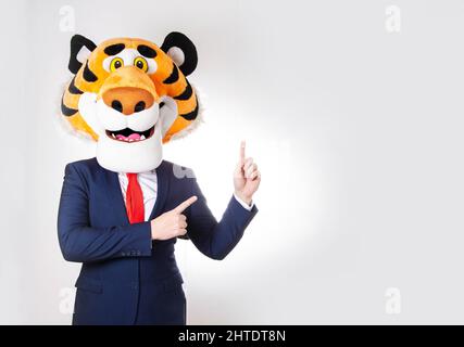 Un homme portant une cravate et un costume d'affaires portant un masque de tigre pointe ses doigts vers l'espace vide pour l'inscription. Banque D'Images