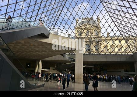 Salle principale pleine de personnes sous la pyramide de verre dans le Musée du Louvre, Paris, France Banque D'Images