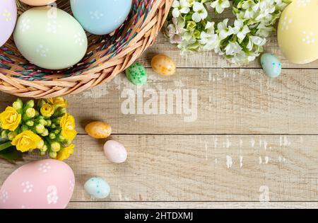 Bordure d'oeufs et de fleurs de pâques autour d'un fond rustique en bois Banque D'Images