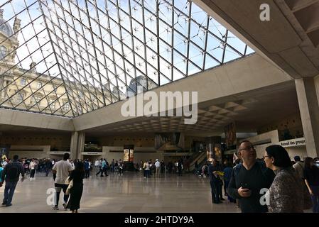 Salle principale pleine de personnes sous la pyramide de verre dans le Musée du Louvre, Paris, France Banque D'Images