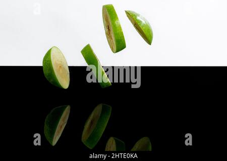 Gros plan d'anneaux de pomme coupés dans l'air sur une surface noire Banque D'Images