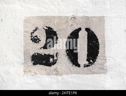 Numéro 20 rétro imprimé en peinture noire sur un mur en brique blanche. Banque D'Images