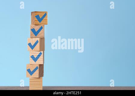 Cubes en bois empilés avec une coche bleue. Concept de la liste de contrôle, objectif atteint, résolution et liste des tâches. Banque D'Images