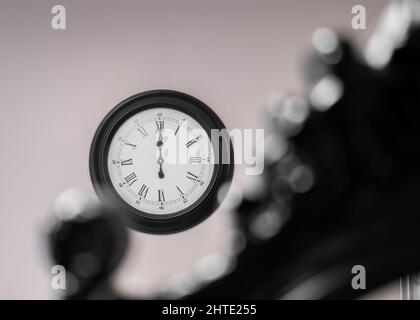 12:00 douze heures sur le mur avec une mise au point créative sélective. Grande horloge murale noire. Banque D'Images