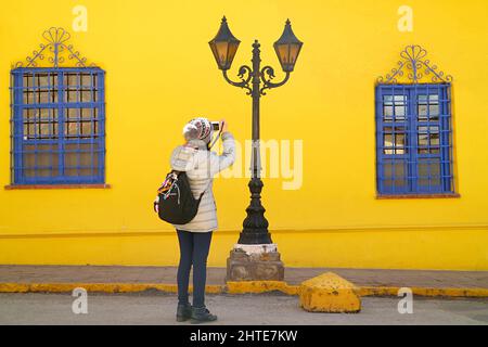 Voyageur prenant des photos d'un lampadaire vintage accrocheur avec un bâtiment aux couleurs vives en toile de fond Banque D'Images