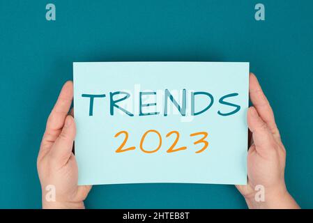 Tendances 2023 est debout sur un papier, mains tenant le signe, communication, marketing, nouveaux concepts, essence fond Banque D'Images