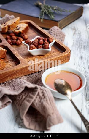 Miel, biscuits et noix. Biscotti italien ou cantuccini fait maison avec amandes et fruits secs sur fond de bois blanc. Biscuits italiens traditionnels Banque D'Images