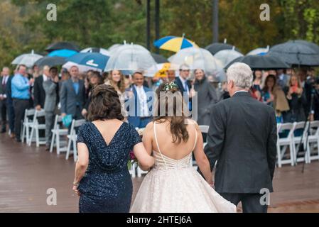 Porter des parasols et une mariée marchant dans l'allée avec ses parents le jour du mariage Banque D'Images