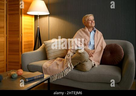 Vieille femme satisfaite enveloppée de couverture relaxante Banque D'Images