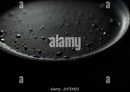 Fait partie d'une casserole vide en fonte de couleur noire avec des gouttes d'huile végétale. Gros plan. Arrière-plan sombre. Commencez la cuisson Banque D'Images