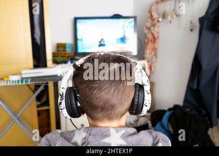 Dos tête sans visage garçon sourd enfant 12 ans portant des écouteurs regardant l'écran jouer jeu d'ordinateur à la maison dans la chambre Royaume-Uni Grande-Bretagne KATHY DEWITT Banque D'Images