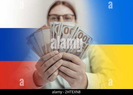 Femme d'affaires couvrant son visage avec de l'argent contre le drapeau ukrainien bleu et jaune et le fond du drapeau russe. La guerre en Ukraine. Banque D'Images