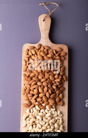 Directement au-dessus de la dose d'amandes et de noix de cajou sur une planche de service en bois sur fond gris Banque D'Images