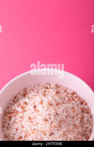 Gros plan du sel de roche himalayan dans un bol sur fond rose avec espace de copie Banque D'Images