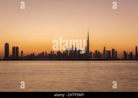 Horizon de Dubai Business Bay avec silhouettes de bâtiments pendant le coucher de soleil brumeux, couleurs orange, longue exposition. Banque D'Images
