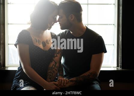 Je veux vraiment vous embrasser. Photo d'un jeune couple affectueux assis près d'une fenêtre. Banque D'Images