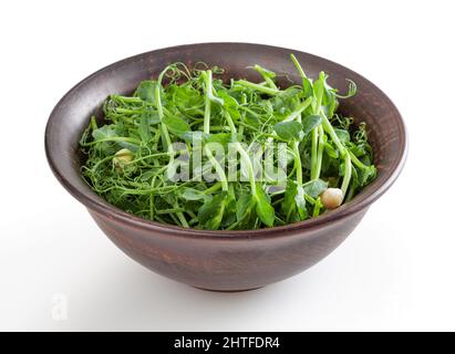 Microverts frais de pois dans un bol en céramique isolé sur fond blanc avec passe-cheveux Banque D'Images