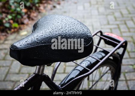 Gros plan d'une selle humide d'un vélo, vélo sous la pluie avec gouttes d'eau sur la selle, mise au point sélective Banque D'Images