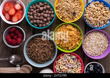 Plein cadre de fruits aux baies avec diverses céréales pour le petit déjeuner dans des bols colorés disposés sur une table Banque D'Images