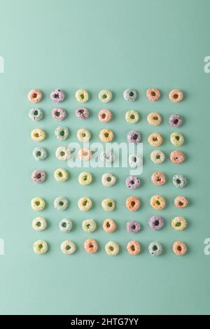 Directement au-dessus de la prise de céréales de petit déjeuner en forme d'anneau coloré disposées sur fond vert Banque D'Images