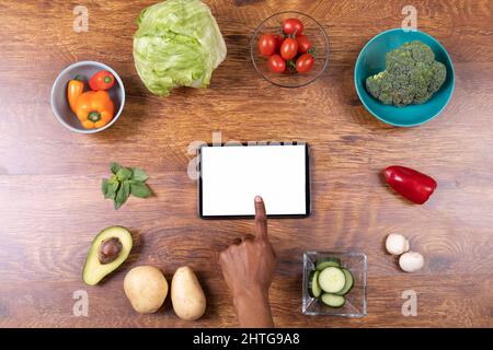Directement au-dessus de la photo de la main coupée à l'aide d'un PC tablette au milieu de divers aliments sur la table, espace de copie Banque D'Images