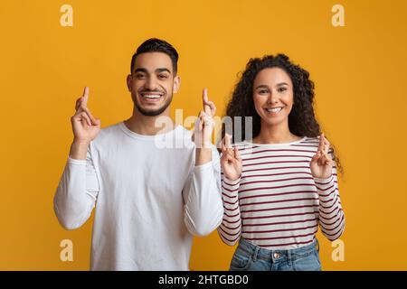 Portrait de l'homme et de la femme arabes heureux croiser les doigts pour la chance Banque D'Images