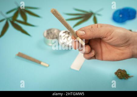 Main avec de la marijuana médicale CBD et des feuilles de chanvre sur fond turquoise. Concept de cannabis médical. Cosmétiques et beauté biologiques et naturels à base de chanvre Banque D'Images