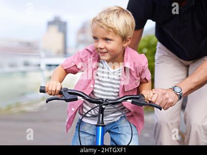 J'adore son premier vélo. Un père enseignant à son jeune fils de faire du vélo. Banque D'Images