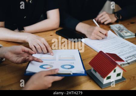 Le jeune couple décide avant de signer le contrat et le prix tandis que le courtier offre le prix exclusif. Concept immobilier. Banque D'Images