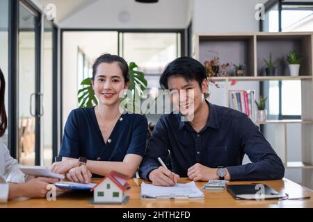 Un jeune couple heureux reçoit une merveilleuse affaire après avoir signé un contrat pour acheter une maison. Concept immobilier. Banque D'Images