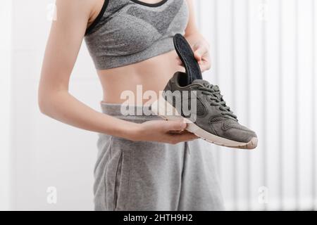 Femme mettant une semelle intérieure orthopédique dans une chaussure à la maison.Sport fille ajustement orthopédique semelle intérieure, gros plan.Bannière de soins des pieds.Correction des pieds plats Banque D'Images