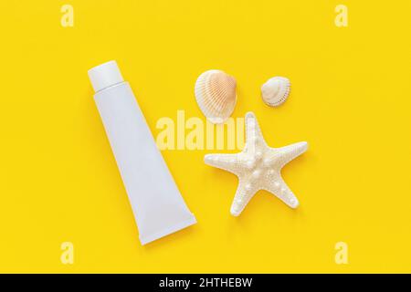 Étoiles de mer, coquillages et tube blanc de crème solaire sur fond de papier jaune. Modèle de maquette pour le lettrage, le texte ou votre conception vue de dessus créative. Banque D'Images