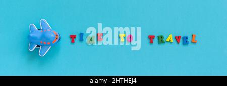 Texte coloré temps de voyage et l'avion jouet drôle des enfants sur fond de papier bleu. Bannière vue de dessus concept tourisme, modèle pour carte postale, accueil Banque D'Images