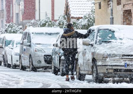 Vue à angle bas d'un garçon qui retire la neige d'une fenêtre de voiture. Banque D'Images