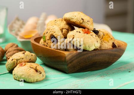 Petits gâteaux de flocons d'avoine frais avec raisins secs, fruits confits, graines de lin et de sésame et noix dans une assiette en bois en forme de cœur Banque D'Images