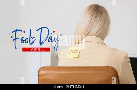 Femme mûre avec du papier collant sur son dos dans le bureau. Fête de la journée d'avril Banque D'Images