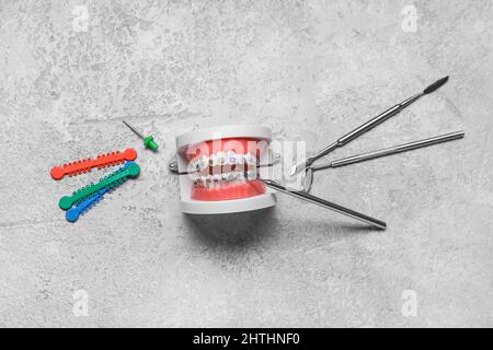 Modèle de mâchoire avec bretelles et outils dentaires sur fond gris Banque D'Images