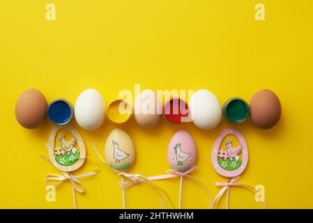 Modèle de Pâques avec œufs de poulet et peintures sur fond jaune Banque D'Images