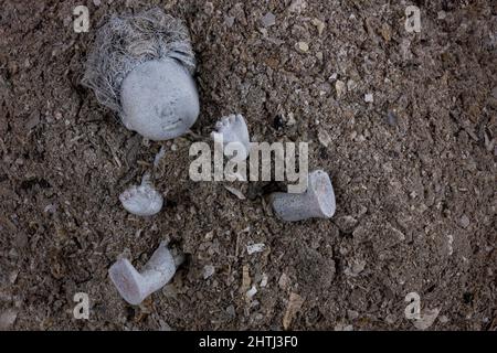 Poupée abandonnée dans un tas de cendres grises. Concept de violence contre le peuple ukrainien. Guerre, dévastation et ruines en Ukraine, 2022. Banque D'Images