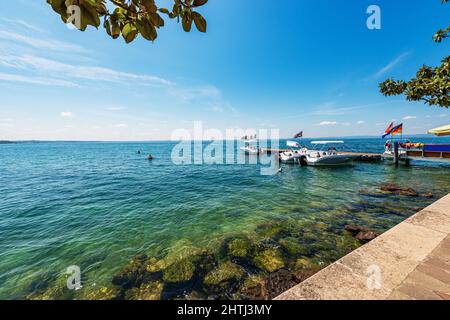 Petits bateaux à moteur amarrés sur la côte du lac de Garde, village de Bardolino, station touristique dans la province de Vérone, Vénétie, Italie, Europe. Banque D'Images